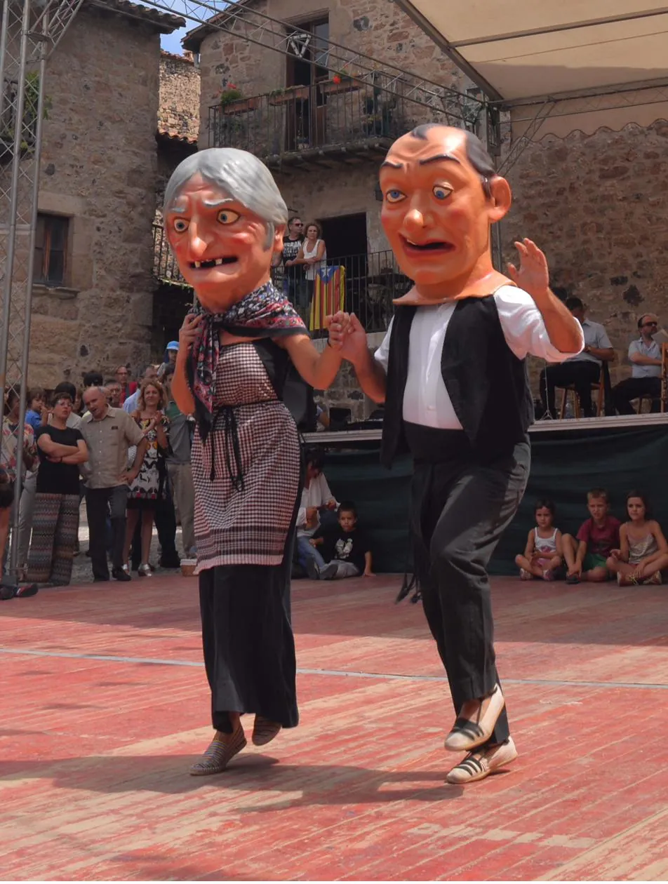 Els gegants de Santa Pau ballant a la plaça durant la festa major, envoltats de gent.