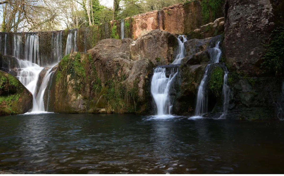 Salt d'aigua entre roques al terme de Santa Pau, amb el corrent caient sobre una bassa.